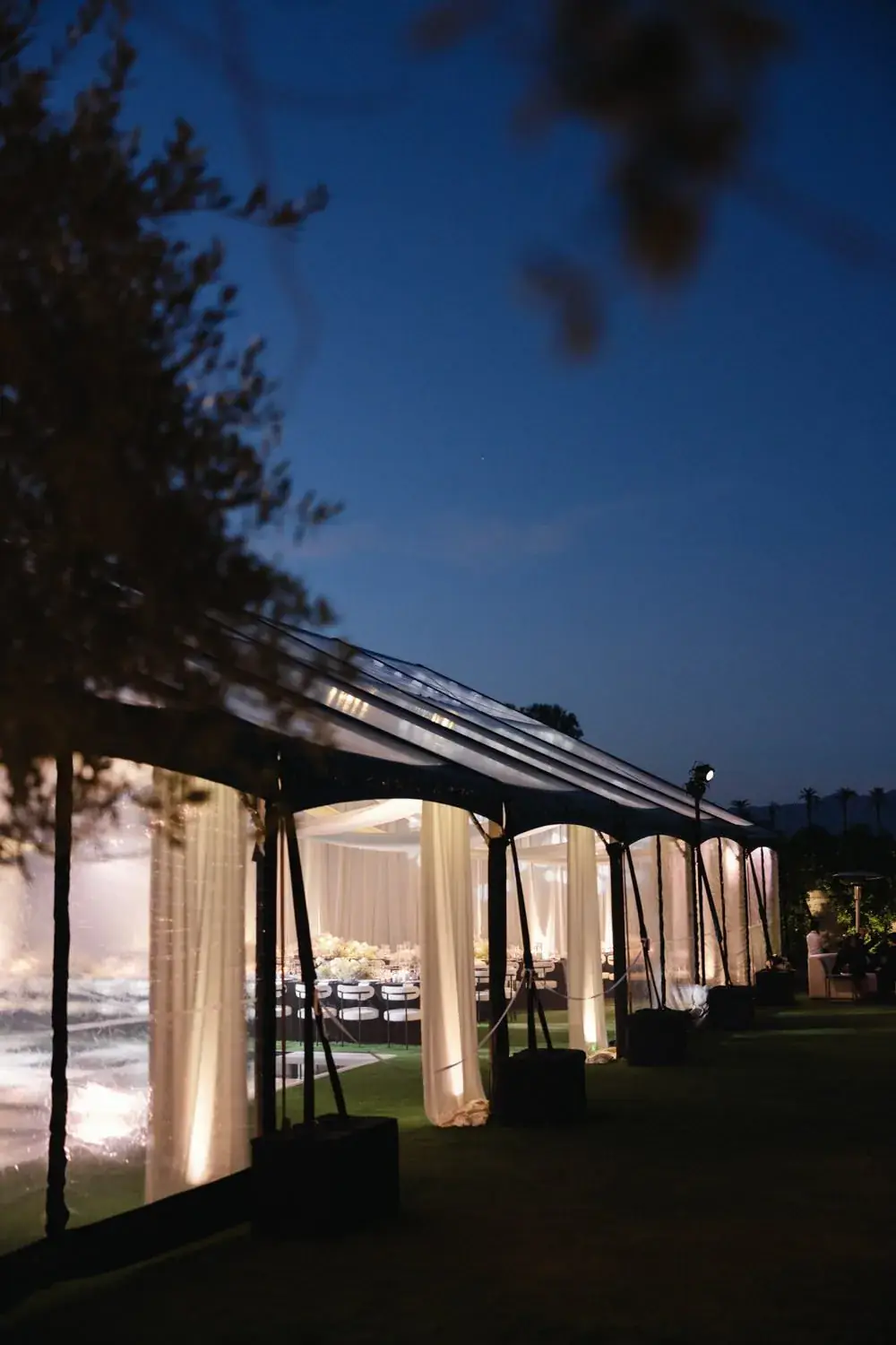 Wedding reception tent lit at night on the estate lawn